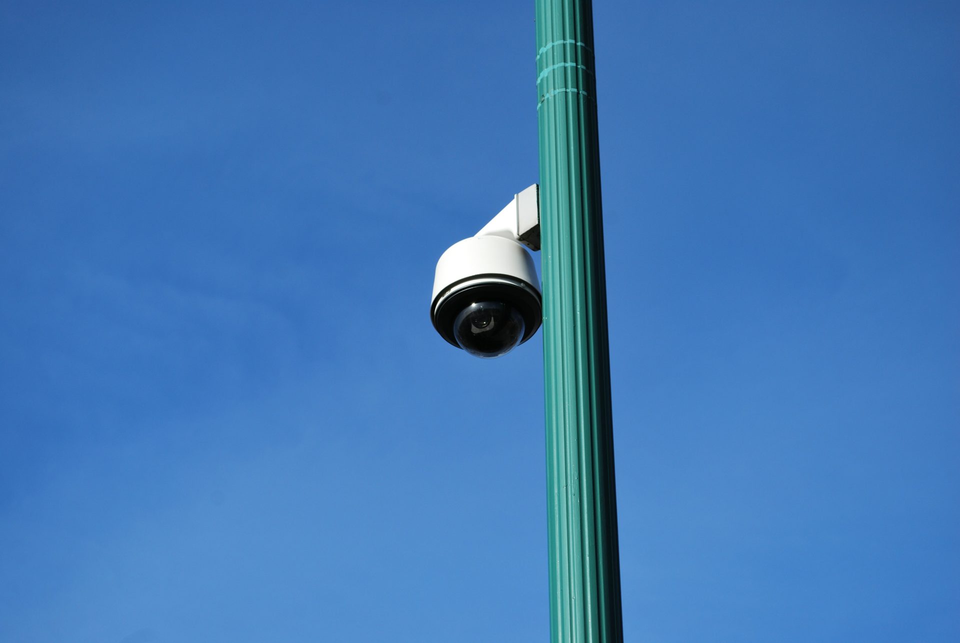 a security camera on top of a green pole